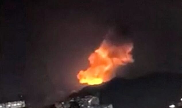 A column of smoke rises during multiple explosions in the early hours of the morning, in Caracas