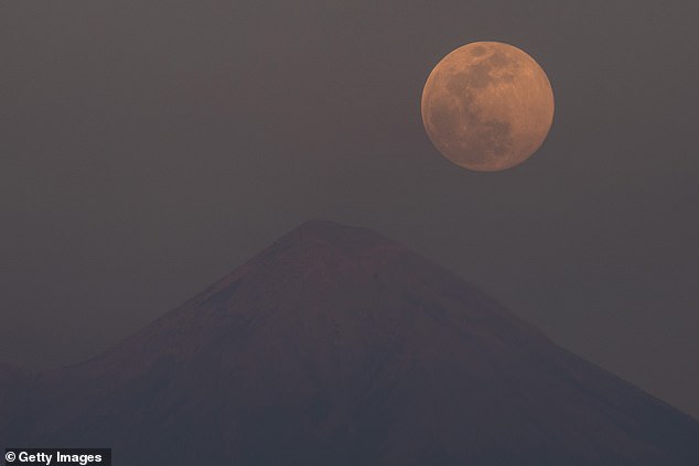 In the Mexican city of Cocoyoc, the Wolf Moon was captured beside the Popocatepetl volcano brighten up the sky in the hazy heat of last night