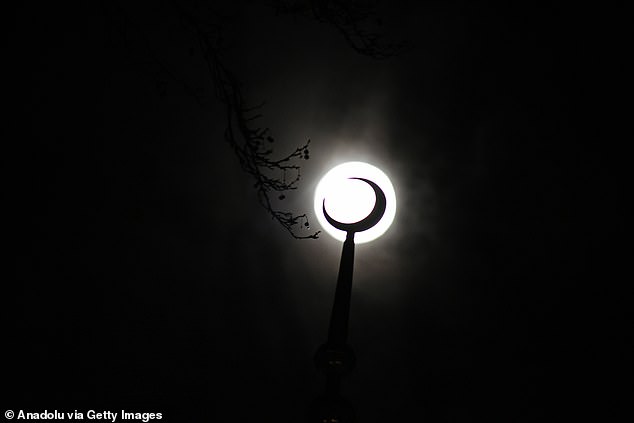 A surreal photo shows the moon behind the crescent moon of mosque's minaret in Srinagar - in Indian-administered Jammu and Kashmir