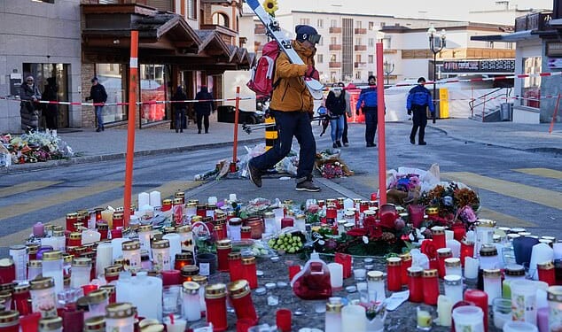 A skier passes candles near the sealed off Le Constellation bar in Crans-Montana, where at least 40 people were killed in a devastating fire during New Year's Eve celebrations