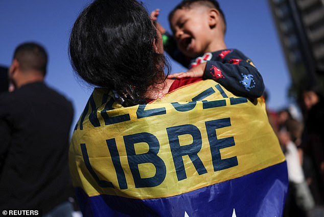 A woman, with a flag on her back reading "Freedom", lifts her son, after U.S. President Donald Trump said that the U.S. attacked Venezuela and deposed its President Nicolas Maduro, in Santiago, Chile January 3, 2026.