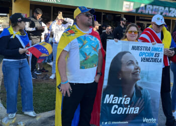 David Nuñez, Lisbeth Garcia, and Victor Gimenez gather outside El Arepazo restaurant with a banner of opposition leader and Nobel Peace Prize winner Maria Corina Machado amid celebrations following news of Venezuelan President Nicolás Maduro's capture in Doral, Florida, on Jan. 3, 2026.