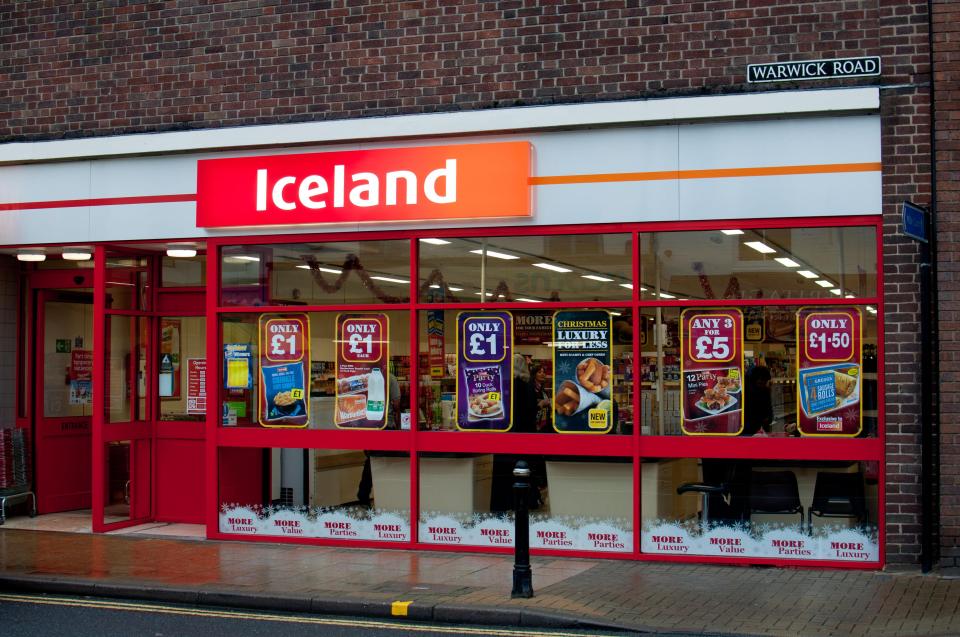 Exterior of an Iceland store displaying sale signs in the windows.