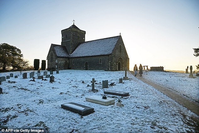 LONDON -- Early morning walkers make their way through the churchyard at St Martha-on-the-Hill Church at sunrise in Chilworth