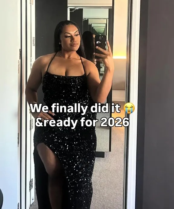 A woman in a black sequined dress takes a selfie in a mirror.