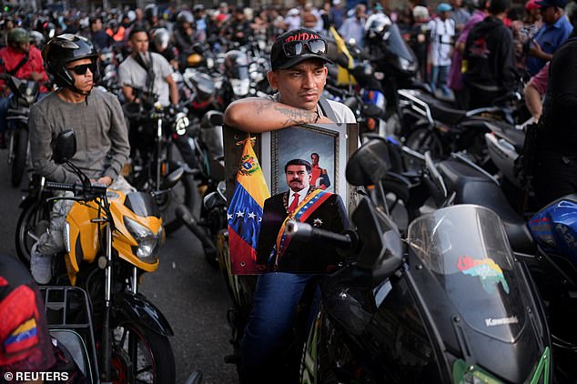 A motorcyclist carries a portrait of Maduro after he was captured following US air strikes