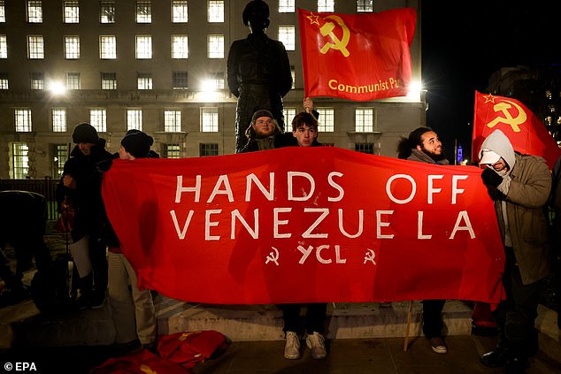 Campaigners hold banners and flags as they protest against the US actions in Venezuela