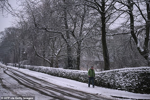 A man walks down a snow-covered street in the Derbyshire town of Glossop this morning