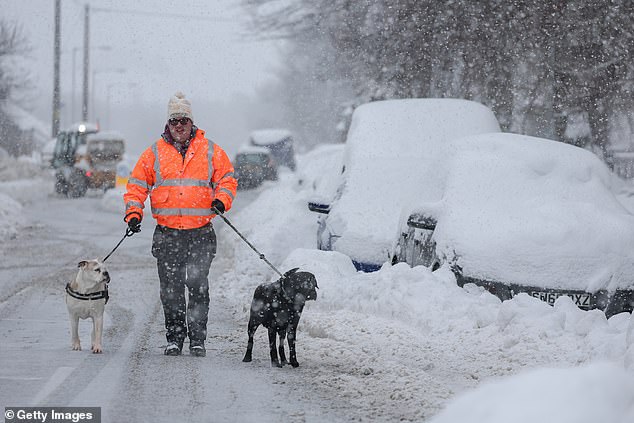 A man walks his two dogs through thick snow in Lumsden, Scotland on Tuesday