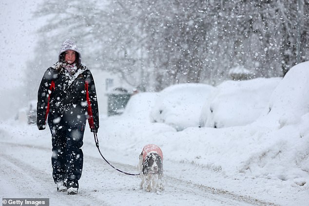 People walk through a snow shower in Lumsden, Scotland, on Tuesday afternoon