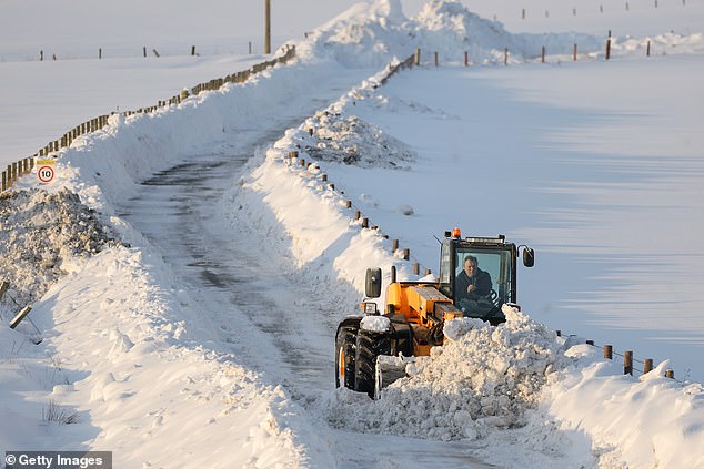 A man clears snow from a road with a digger near Gartly in Aberdeenshire on Tuesday morning