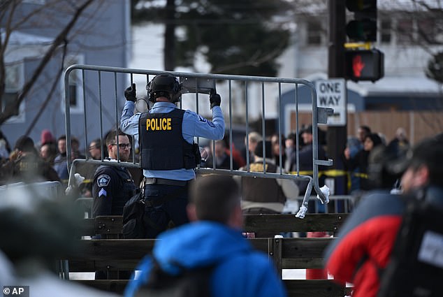 Pictured: A police officer moving metal barriers in front of the protesters