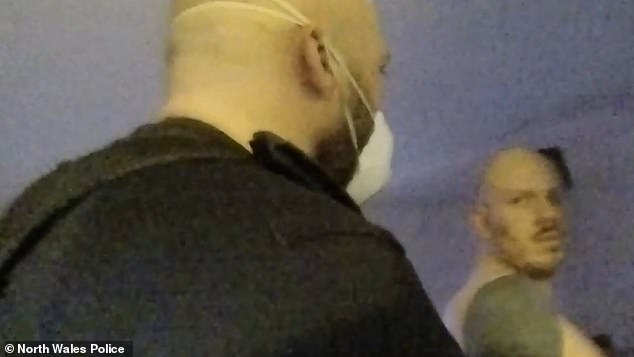 Miles Cross (right) is seen being arrested at his house in Wrexham, North Wales, in January last year