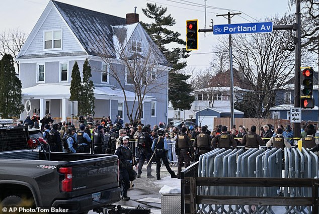 Law enforcement officers line a Minneapolis street as protesters gather in the city