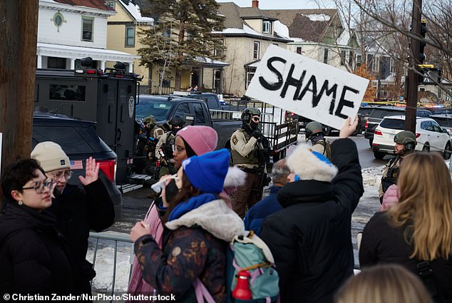 A group of protesters hold placards near the scene of the shooting earlier today