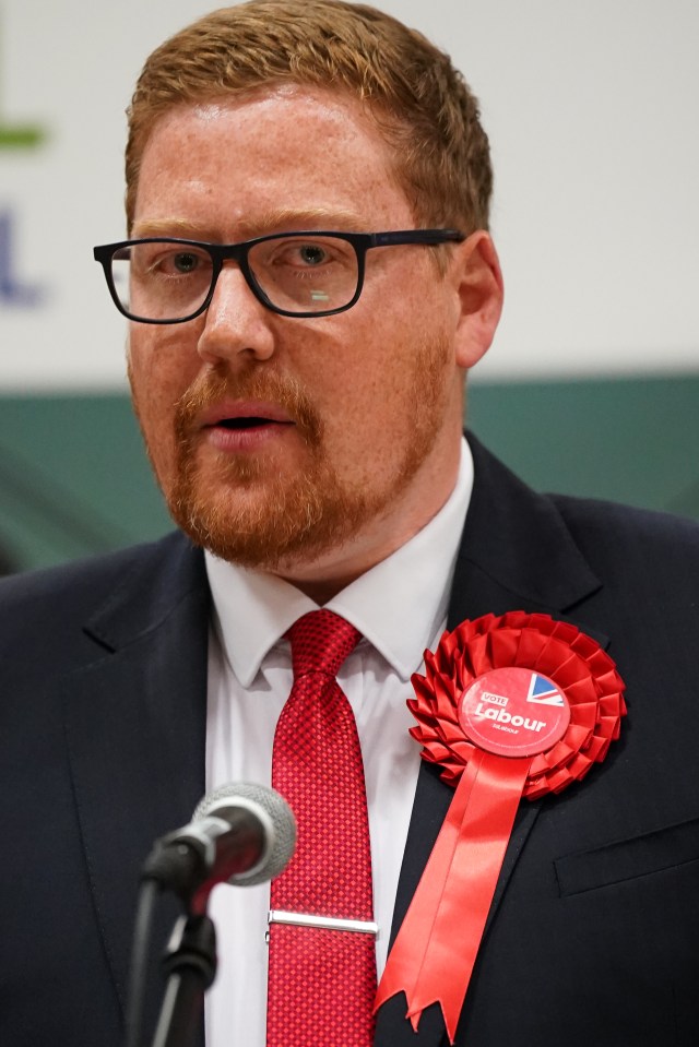 Jonathan Brash speaking at a podium with a Labour Party rosette pinned to his lapel.