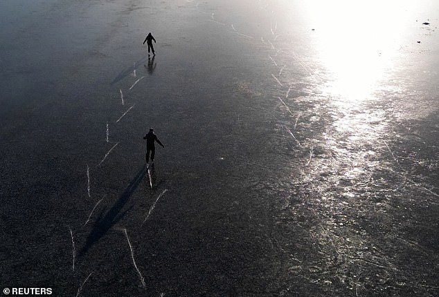 Two people skate across a frozen flood plain at Port Meadow in Oxford on Wednesday