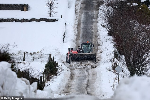 A worker clears snow from a road in the Aberdeenshire village of Drumoak on Wednesday
