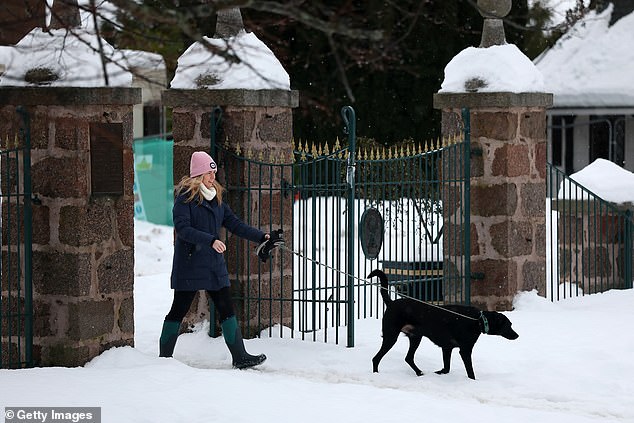 A woman walks her dog in Aboyne, Aberdeenshire, today following further snowfall overnight