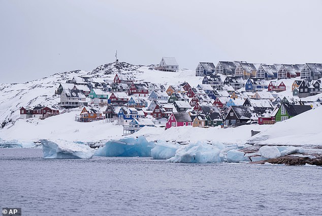 A scattering of brightly coloured houses covered by snow next to the sea in Nuuk, Greenland