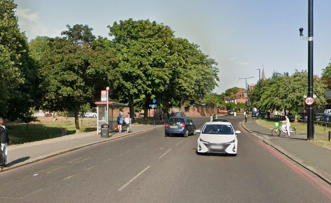 A street in Tooting with cars, a bus stop, and people walking and cycling.