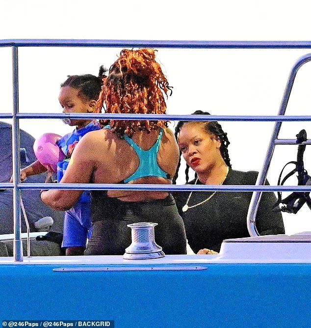 The toddler peacefully cuddled up with his little sister as their big brother jumped around from various friends and family members