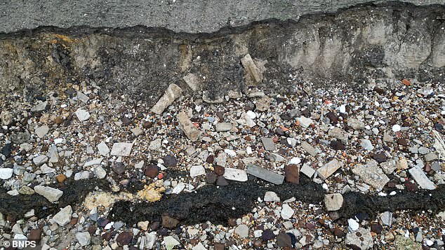 Old building bricks, tiles and an exposed pipe are seen at the beach after it was eroded away by the sea