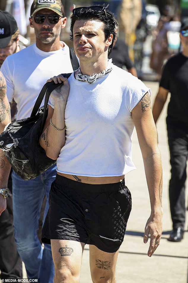 He carried his belongings in a black tote bag and accessorised with a gold wrist chain, black-and-white scarf and sunglasses perched atop his head