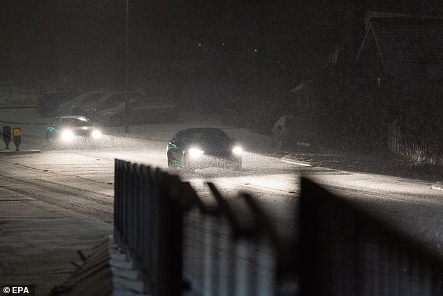 Motorists drive on a snow-covered road in Ruthin, Wales, on Thursday night