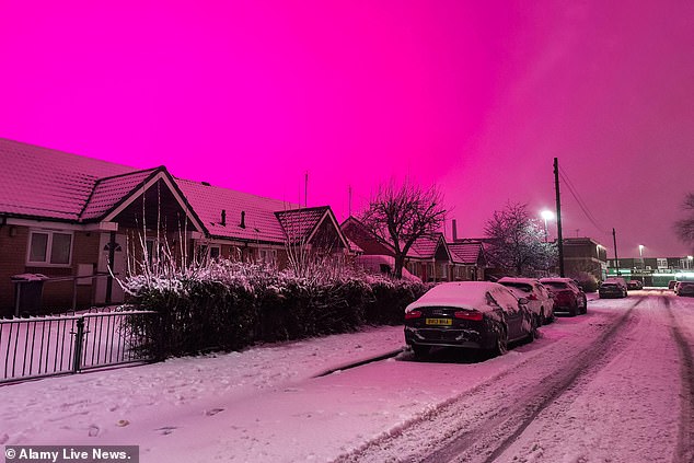 The sky turns pink during snowfall in the Small Heath area of Birmingham early this morning