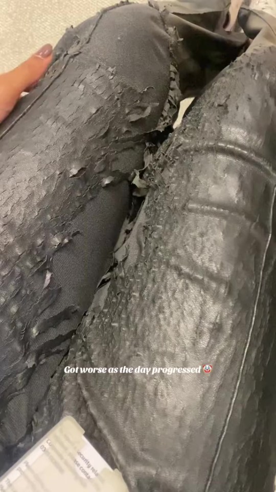 A pair of black faux leather pants with the coating peeling off significantly.