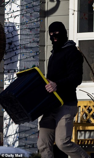 Another agent wearing a balaclava walked out with a storage bins of the agent's belongings