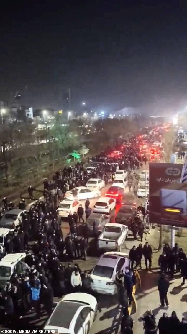 Protesters mill around cars jamming a main road in Mashhad, 560 miles from Tehran