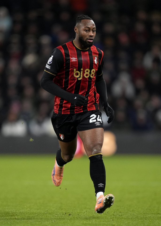 Antoine Semenyo running on a soccer field in a red and black striped jersey with the number 24.