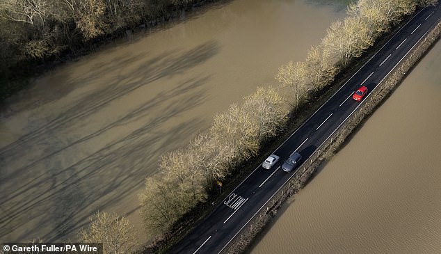 Motorists cross floodwaters from the River Beult near Ashford in Kent