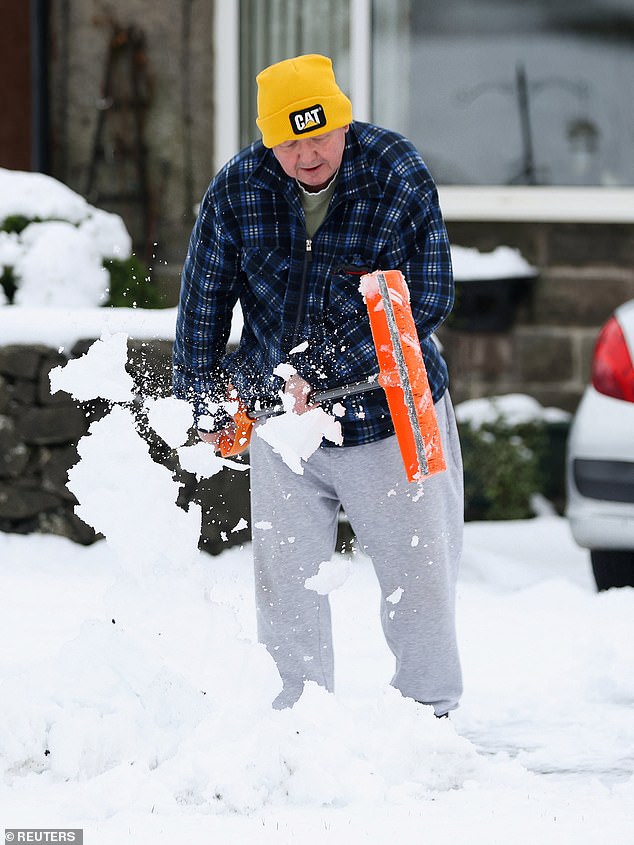 A man clears snow from his front garden at Dove Holes in Derbyshire on Friday morning