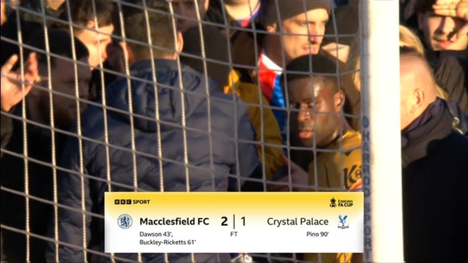 A soccer match scoreboard shows Macclesfield FC beat Crystal Palace 2-1, with spectators visible behind a goal net.