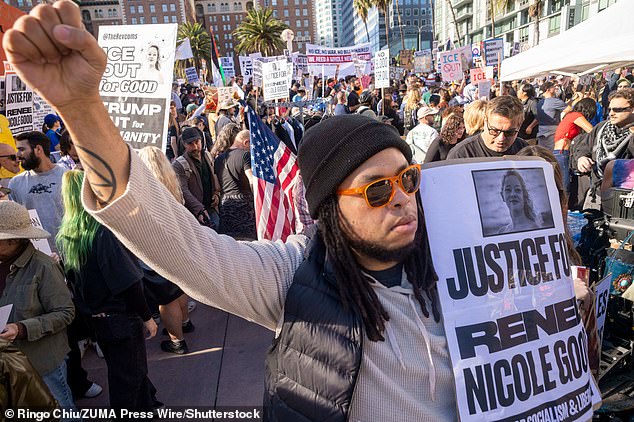 A protester raises a fist as others hold signs during a demonstration calling for an end to federal immigration enforcement operations