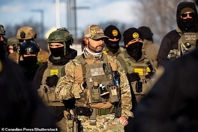 Federal agents look on as protesters gather during a rally for Renee Good in Minneapolis