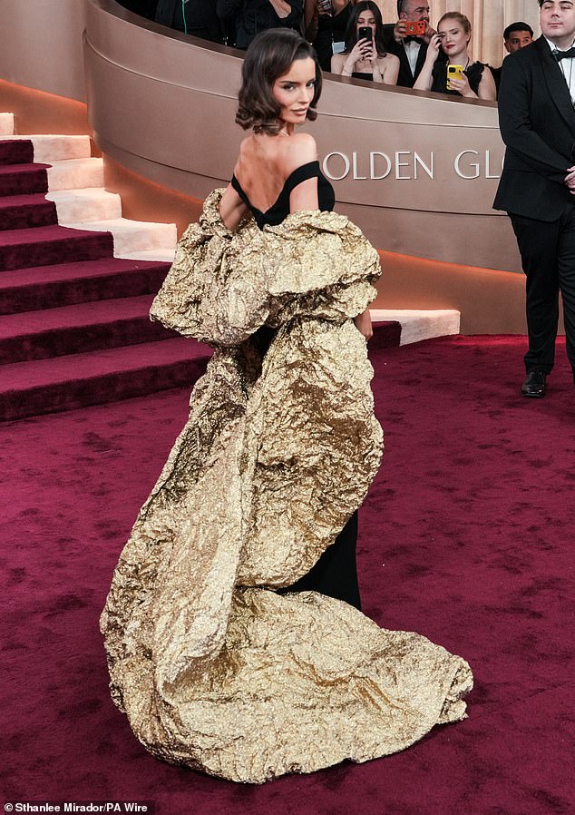 Love Island star Maura Higgins wore quite the over-the-top dress on the Golden Globes red carpet, as her black dress featured a crumpled golden cape in the back. The cape trailed all the way down to the floor behind her, as she kept her short hair in simple curls