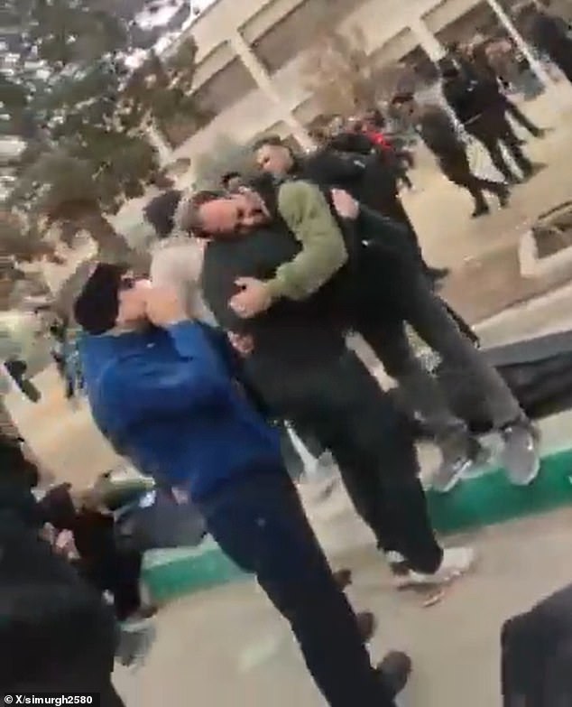 Two mourners console each other outside the medical facility in Tehran