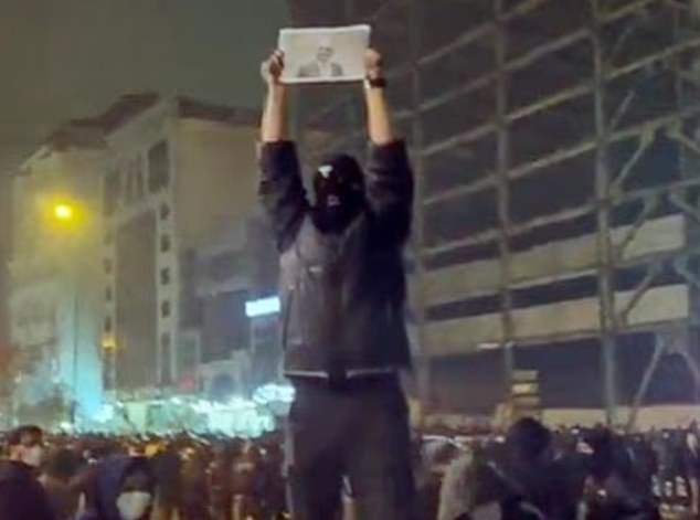 A protester holds aloft a portrait of the exiled son of Iran's last shah amid a crowd in footage from Iran