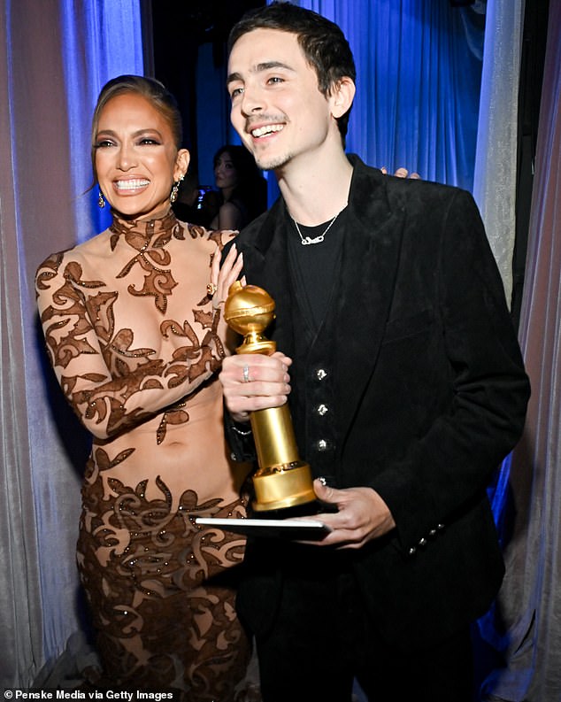 The pair flashed cheerful smiles as they strolled side-by-side backstage as he proudly held his award