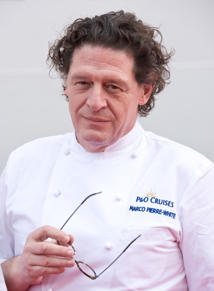 Marco Pierre White, a British chef, holding glasses and wearing a white chef's jacket with "P&O Cruises" and his name embroidered on it.