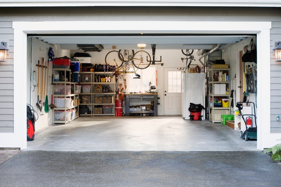 A clean, well-organized garage with bikes, shelving units, tools, and a workbench.