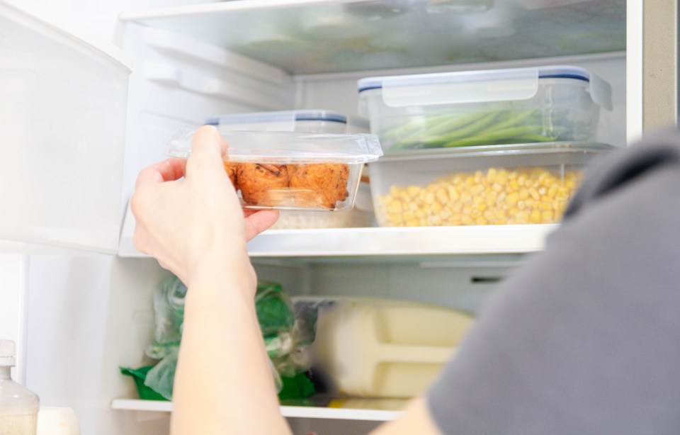 A person storing packed food containers with leftovers in a refrigerator.