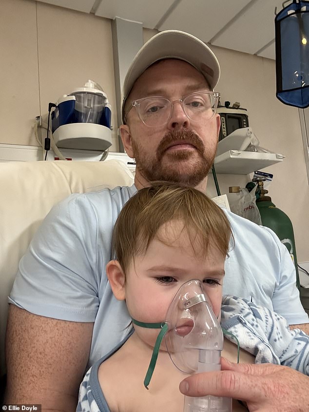 Ellie's husband, Michael Doyle, 41, holds their two-year-old daughter Norah, as she gets a nebulizer treatment in the ship's infirmary