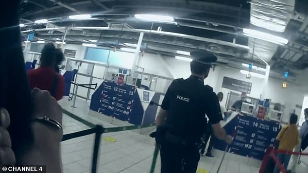 Holub is led through Luton Airport as an officer quips: 'At least you get to beat the queues'