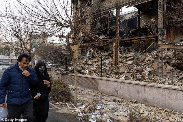 People pass by a destroyed building on January 10, 2026 in Tehran, Iran