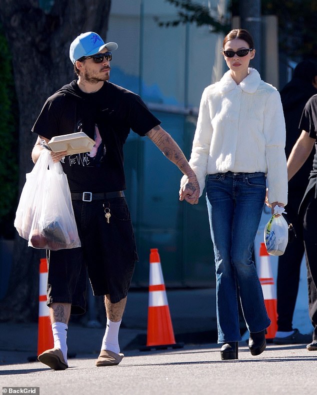 He hung a jumper over his shoulder while carrying a bag of items from the market and walking in slipper shoes and socks